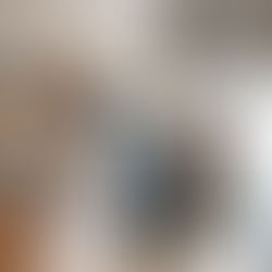 Woman in a grey shirt holds salad in an office kitchen, smiling. Two people converse by a snack vending machine in the background.