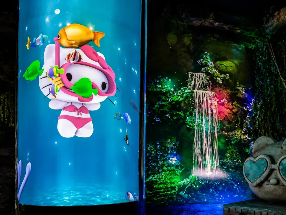 Sala con proyecciónes donde se ve a Hello Kitty buceando en una pecera , una cascada 3D y una escultura de HK