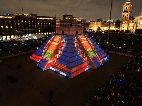 maqueta monumental de pirámide, se video proyecta sobre las 4 caras. la pirámide esta rodeada de publico en el zocalo