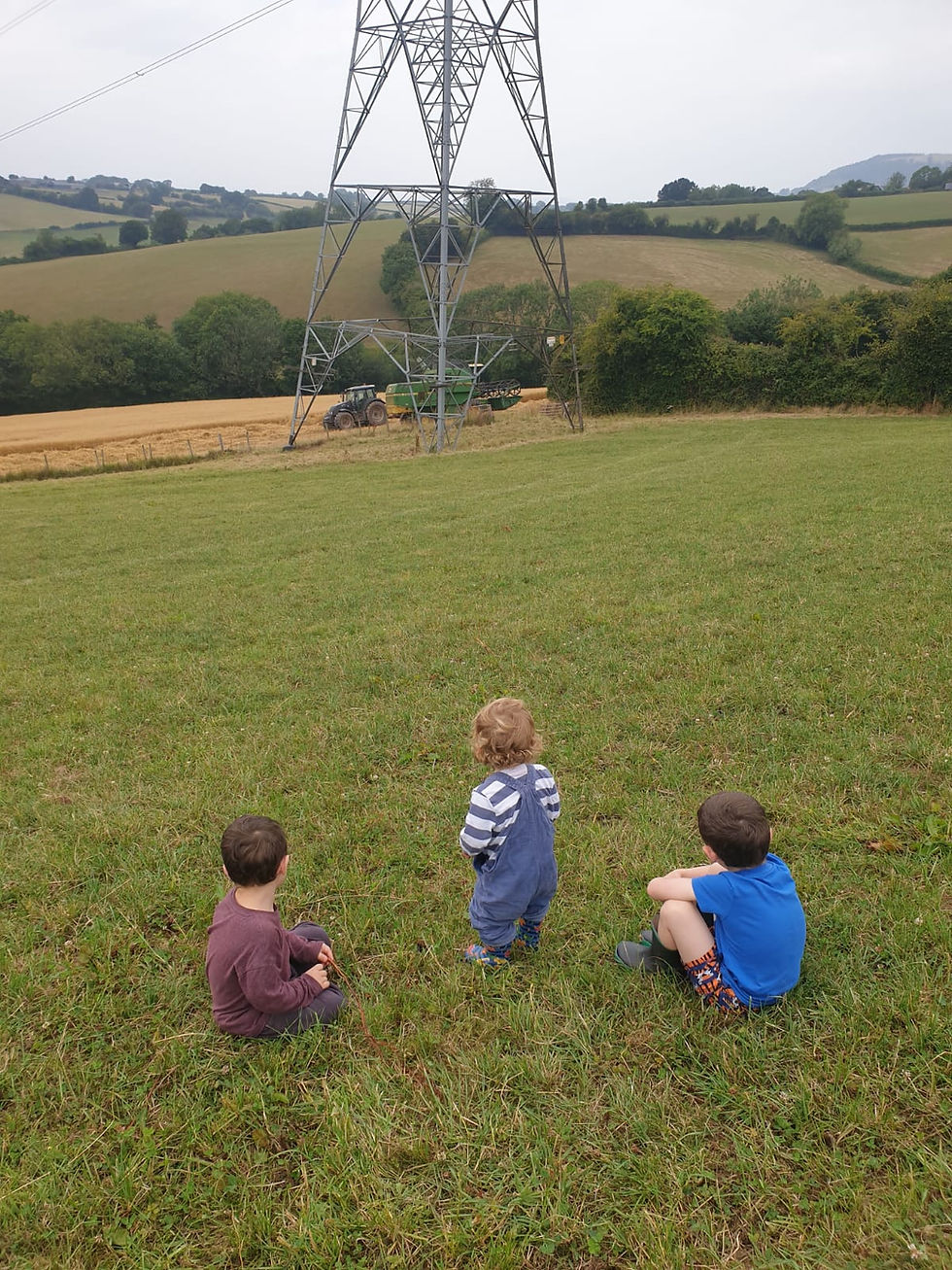 three children watching a combine harvester