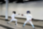 Two youth fencers lunging Athena Fencing Club