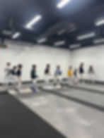 Beginner and novice fencing class lining up for drills at Athena Fencing Club.