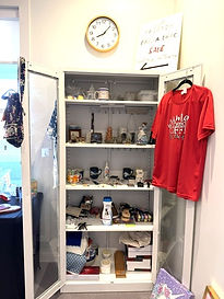 Displayed cabinet featuring clothing and donated household items for sale at the Marie Federico Bric -A -Brac Boutique