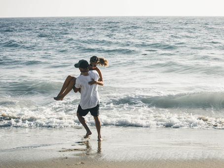 Husband and wife playing on the beach together during their summer vacation.