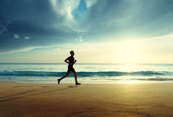 Man running on tropical beach at sunset.