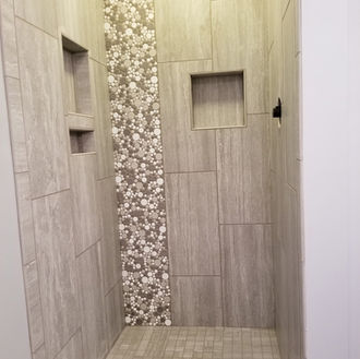A modern shower install using large-format tile for a clean, minimal look, with a vertical pebble mosaic feature strip for contrast and texture. Finished with precise niche work and a layout that keeps everything balanced and intentional.