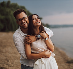 Husband and Wife on beach holding each other happy