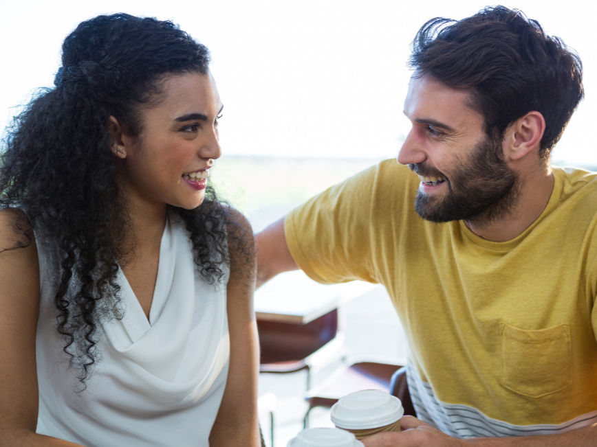 A young couple smiling at each other and talking during a counseling session.