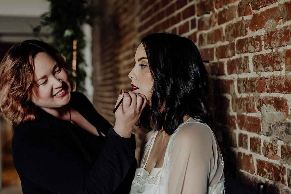 A Nashville bridal hair and makeup trial in progress as a professional makeup artist applies lipstick to a bride wearing a white robe before her wedding, helping refine her wedding-day beauty look.
