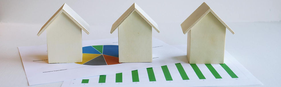 Three wooden London house models on reports with a green bar chart and pie chart, suggesting home finance planning.
