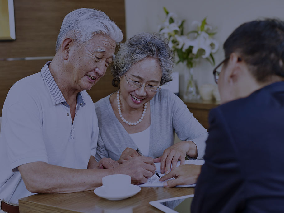 Elderly Asian couple signing documents with a financial advisor.