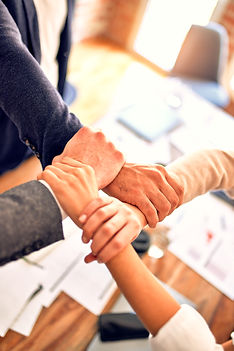 Group of business workers standing with hands together doing symbol at the office_edited.j