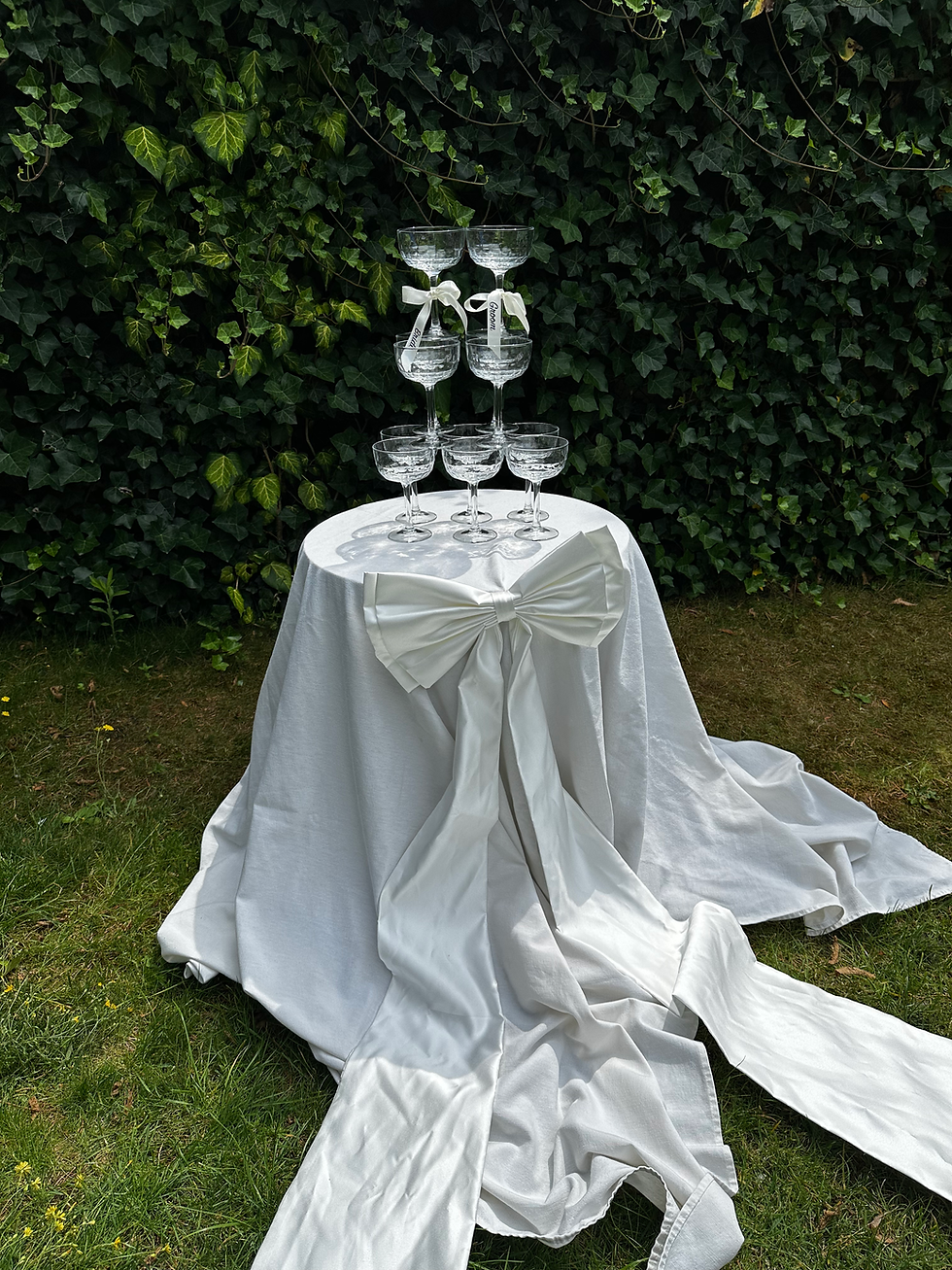 champagnetoren met grote, personaliseerbare satijnen strik, elegante bruiloftsdecoratie in ton-sur-ton ivoor
