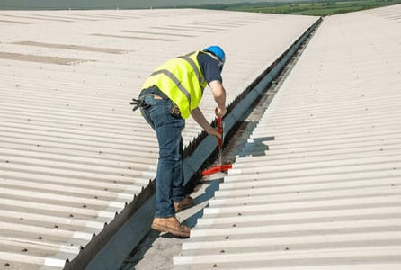 A professional wearing a hard hat and protective gear cleaning a roof