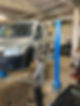 A mechanic examining a van elevated by a lift in a garage