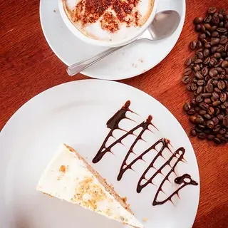 Cappuccino with heart design, slice of cheesecake