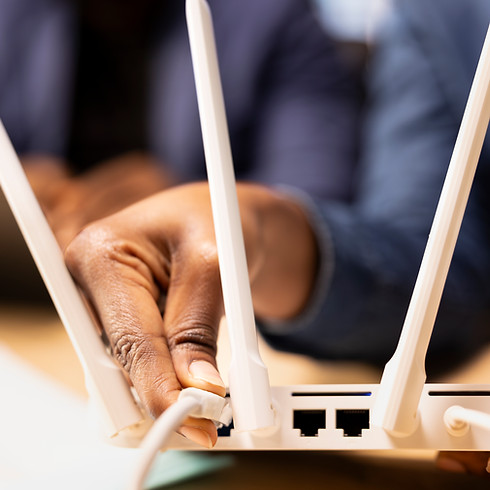 A person connects a cable to a white Wi-Fi router