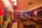 Colorful restaurant interior with purple walls, vibrant artwork, and set dining tables