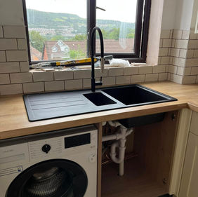 Kitchen with a double sink, black tap, and a washing machine underneath