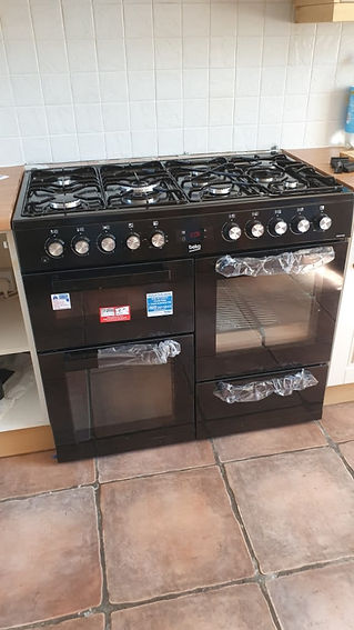 A black double oven with six burners on top, set against a tiled backsplash