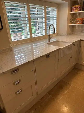 Restored light stone countertop with a white farmhouse sink demonstrating expert surface care