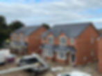 Two new brick houses under construction, with scaffolding, tools, and construction materials