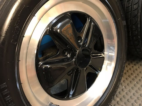 Close-up of a sleek black alloy wheel with five spokes and a polished metal rim
