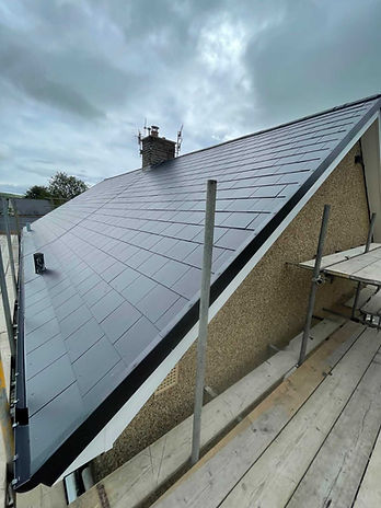 Newly layed tiles on a pitched roof of a house, with scaffolding on the side