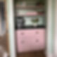 A pink cabinet with a coffee machine on top and a vase of tulips