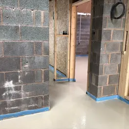 The interior of a house with liquid screed floor and brick walls, and wooden frames