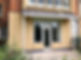 Exterior of a house with a beige wall, white door, and a balcony above
