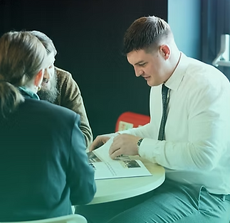 Three people sit around a table reviewing documents in a professional setting
