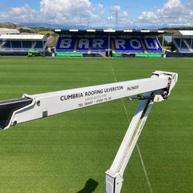 A cherry picker extends over a green football pitch