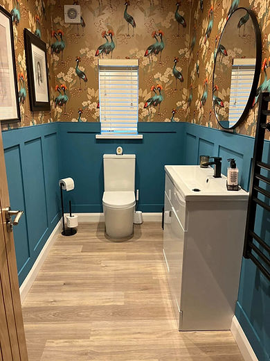 Stylish bathroom featuring floral bird wallpaper, turquoise wainscoting, and a white vanity