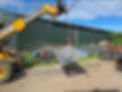 A yellow crane lifts a large metal sheet using a chain