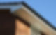 Close-up of a house corner showing a black gutter and white fascia