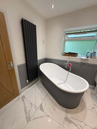 Freestanding grey bathtub on marble tile floor