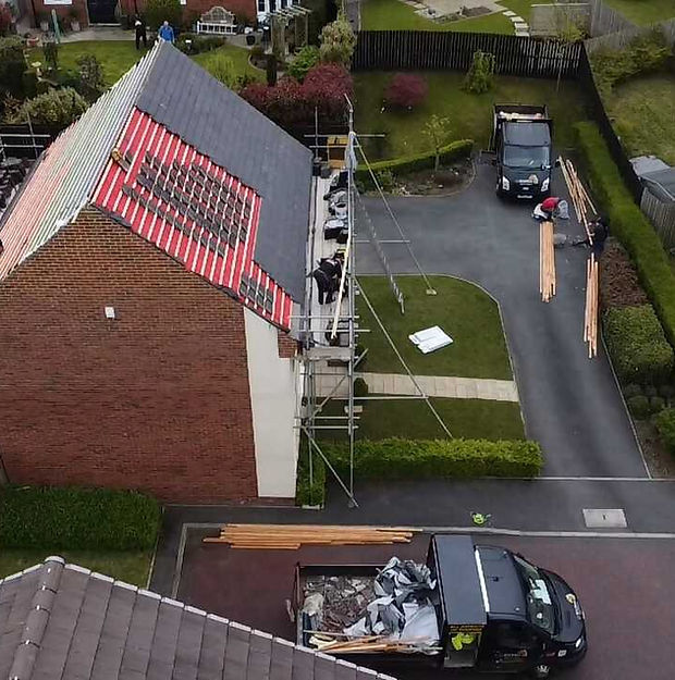 Aerial view of a house with a partially red-tiled roof and scaffolding on the side