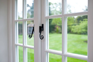A close-up view of a white-framed window with black, ornate handles