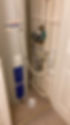 A large hot water tank with blue panels in a small room with numerous pipes and a control panel