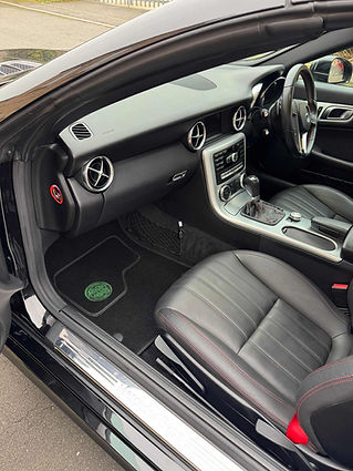 Car interior featuring black leather seats with red stitching, metallic accents, and a sleek dashboard