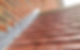 Close-up of a brick wall and sloped roof intersection, featuring red tiles and metal flashing for weatherproofing