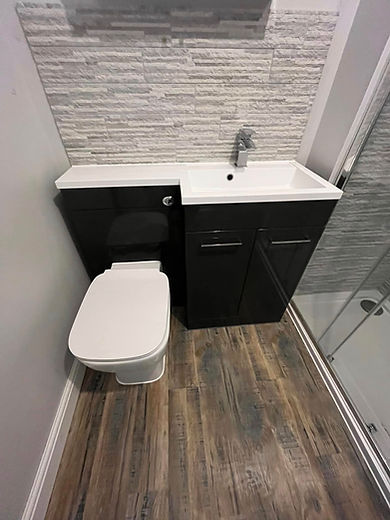 Bathroom featuring a sleek black vanity with a white sink, a white toilet