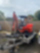 A red mini excavator and a red mini dumper are loaded on a trailer in a gravel driveway