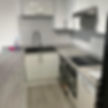 Kitchen featuring sleek white cabinetry, grey countertops, a black sink, and integrated appliances, including a washing machine
