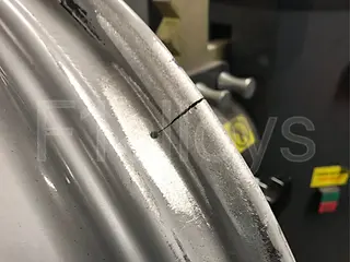 Close-up of a damaged aluminium wheel showing a noticeable crack along the rim surface