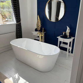 Bathroom with a white freestanding bathtub, floor with a round mirror, and blue accent wall