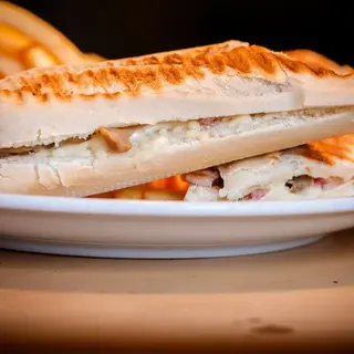 Grilled panini sandwich with cheese and ham on a plate