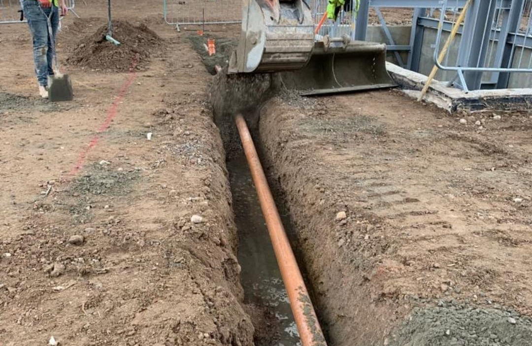 An excavator covering an underground pipe