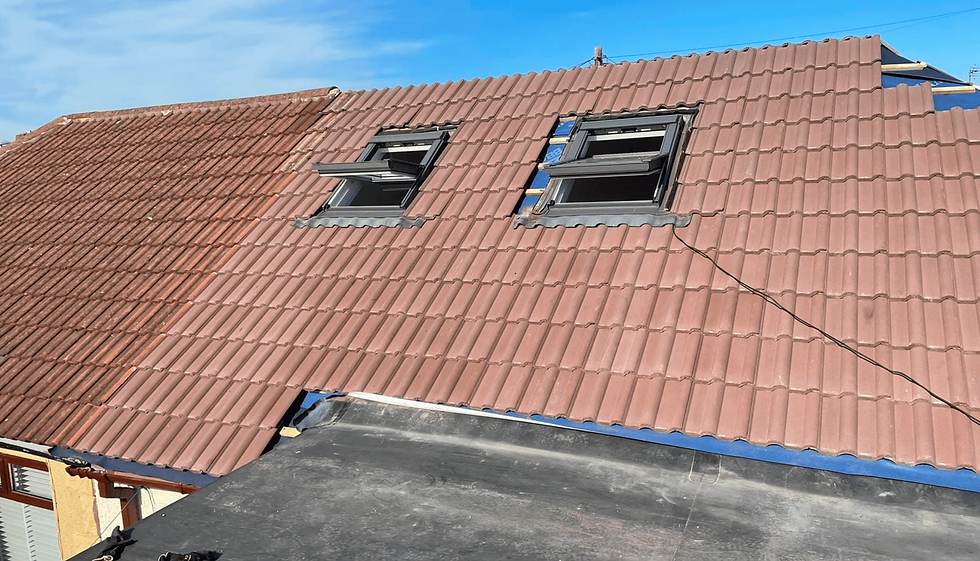 Red-tiled roof with two open skylights, partially replaced tiles, and clear blue sky above